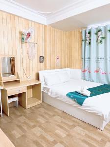 een slaapkamer met een bed, een bureau en een televisie bij Khách sạn Trí Đức in Da Lat