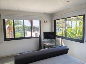 a living room with a couch and two windows at Vаrаndаs dо Sоl-Vista relaxante entre mar e montanha in Ponta do Sol