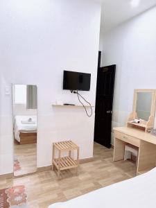 een woonkamer met een tv aan de muur en een kruk bij Khách sạn Trí Đức in Da Lat