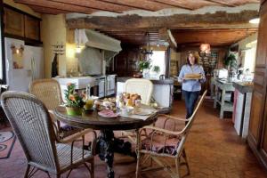 a woman walking through a kitchen with a table at Le Grand Logis in Marchais