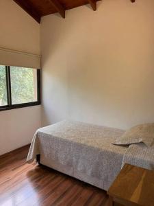 a bedroom with a bed and a wooden floor at Departamento con pileta y asadores in Villa General Belgrano