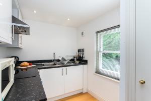 a kitchen with white cabinets and a window at Longridge Road Apartments By Viridian Apartments in London