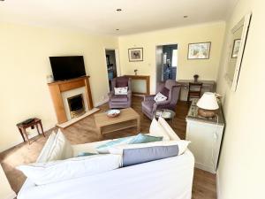 een woonkamer met een witte bank en een open haard bij Daisy Cottage by NewFo rest in Lymington +28 foto's