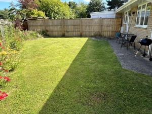 een achtertuin met een hek en een gazon met stoelen bij Daisy Cottage by NewFo rest in Lymington