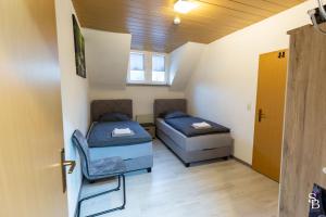 two beds in a room with a door and a chair at Hochrhein Ferienwohnung in Albbruck