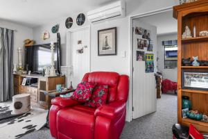 a red leather chair in a living room at The Bach at Old Broadway - Waikuku Beach Retreat in Waikuku Beach