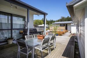 a patio with a table and chairs and a piano at The Bach at Old Broadway - Waikuku Beach Retreat in Waikuku Beach
