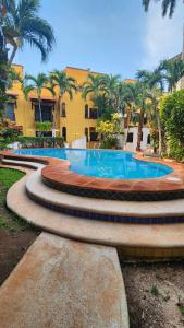 a pool with palm trees in front of a building at Casa Kalily Sol in Playa del Carmen