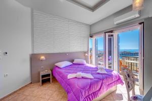 a bedroom with a purple bed and a balcony at Ethrion in Ermoupoli