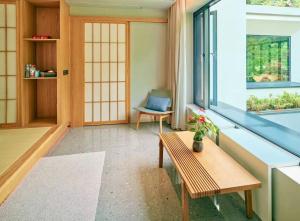 a living room with a bench and a window at 峨眉山和院一溪清音酒店 in Emeishan City