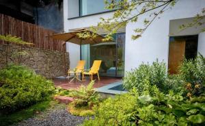 a patio with two chairs and an umbrella at 峨眉山和院一溪清音酒店 in Emeishan City