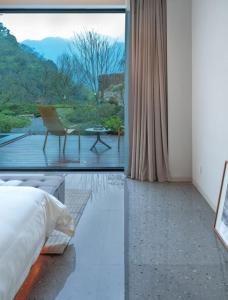a bedroom with a bed and a view of a patio at 峨眉山和院一溪清音酒店 in Emeishan City