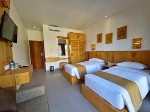 a hotel room with two beds and a flat screen tv at Kamandaka Living in Kuta