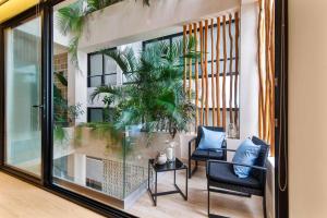 a balcony with two chairs and a glass window at Stunning 2BR with Plunge Pool - Rooftop Sea Views in Playa del Carmen