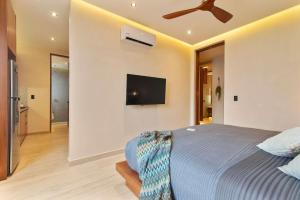 a bedroom with a bed and a tv on the wall at Stunning 2BR with Plunge Pool - Rooftop Sea Views in Playa del Carmen