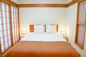 1 dormitorio con 1 cama blanca grande y ventanas en Midland Hotel-秋葉原8分4階建て4LDK貸切別荘, en Tokio