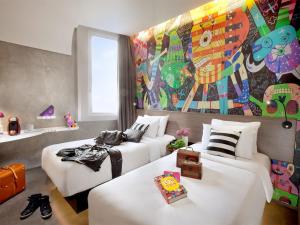 ジャカルタにあるARTOTEL Thamrin Jakartaのベッド2台とカラフルな壁画が備わる客室です。 +47枚の写真