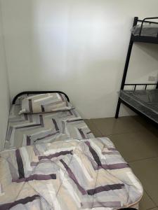 an unmade bed in a room with a bench at Hostel TTDI in Shah Alam