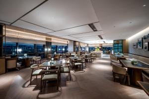 a restaurant with tables and chairs and windows at Qinglian Jinghe Hotel Wuhan Zoo International Expo Center Branch in Han-yang-hsien
