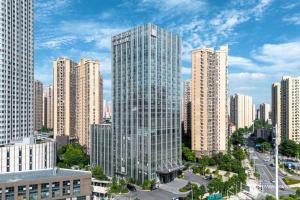 a tall glass building in the middle of a city at Qinglian Jinghe Hotel Wuhan Zoo International Expo Center Branch in Han-yang-hsien