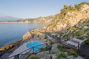 a swimming pool on a cliff next to the water at UNAHOTELS Capotaormina in Taormina