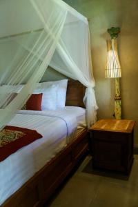 a bedroom with a bed with a canopy and a lamp at Melati Bali 2 in Canggu