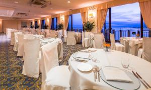a banquet room with white tables and white chairs at UNA HOTELS Capotaormina in Taormina