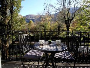 uma mesa com duas cadeiras sentadas numa varanda em Charmant T2 avec balcon, parking et lave-linge près du parc - FR-1-313-235 em Luchon