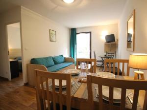 uma sala de estar com uma mesa e um sofá azul em Charmant T2 avec balcon, parking et lave-linge près du parc - FR-1-313-235 em Luchon