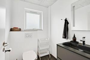 a white kitchen with a sink and a window at Beautiful Holiday Home For 2 Families Near Grenaa Beach in Grenå +22 photos