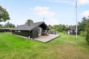 a cabin with a wooden deck in a field at Cottage Near St Sjørup For 6 People in Ørsted