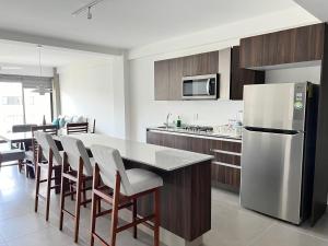 ヌエボ・バジャルタにあるNuevo Vallarta Condo nuevo y moderno a 5 min de playas PTRC17の冷蔵庫と椅子付きのテーブルがあるキッチン