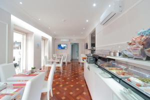 una cucina con banconi bianchi e tavoli e sedie bianchi di Relais Trevi 95 Boutique Hotel a Roma