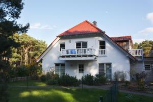 ein weißes Haus mit einem Balkon und einem Hof in der Unterkunft Sommerhaus Thiessow in Thiessow