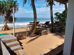 a beach with benches and palm trees and the ocean at Asiri Yoga Retreat in Galle