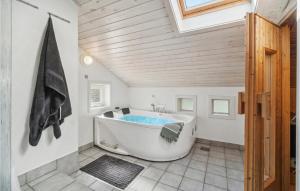 a bathroom with a large tub in a room with wooden ceilings at Beautiful Home In Nexø With Kitchen in Neksø