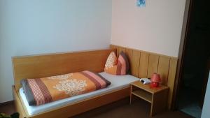 uma cama de madeira com almofadas e uma mesa em Pension und Berggasthaus Kapellenstein em Geyer