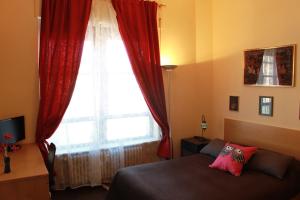 ローマにあるLupa Romeのベッドルーム1室(ベッド1台付)、赤いカーテン付きの窓が備わります。