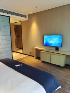 a room with a bed and a flat screen tv at Echarm Hotel Xingyi Menglecheng Kratie Plaza in Xingyin Wanfenglin Airport