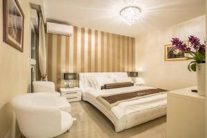a white bedroom with a bed and a chair at Guest House Benedict in Split