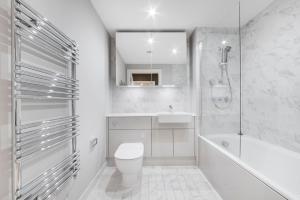 a white bathroom with a toilet and a tub and a sink at Modern 2 Bed Heart of Elephant Castle in London +16 photos