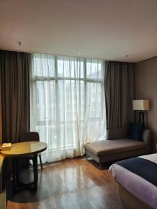 a bedroom with a bed and a table and a window at Echarm Hotel Xingyi Menglecheng Kratie Plaza in Xingyin Wanfenglin Airport