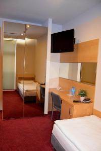 a hotel room with two beds and a desk and a mirror at Hotel Kolna in Kraków