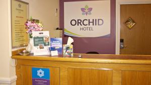 a counter with a hotel sign and flowers on it at Orchid Epsom; Sure Hotel Collection by Best Western in Epsom