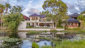 a house with a pond in front of it at Villa Viola 7 Bedroom, Fully Staffed, on the Golf Course in Laguna Phuket