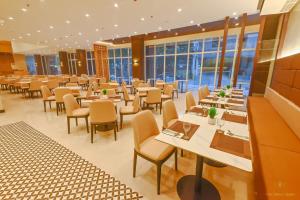 ein Restaurant mit Tischen, Stühlen und Fenstern in der Unterkunft The Tribute Hotel in Manila