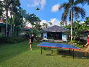 a man standing next to a ping pong table at Reef Hostel in Puerto Princesa City