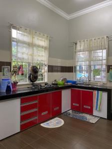 a kitchen with red and white cabinets and windows at dRose Homestay in Kuala Terengganu