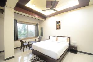 ナスドワーラにあるHotel shree Dhwaja Inn - 100 meter from shreenathji Templeのベッドと机と窓のある寝室