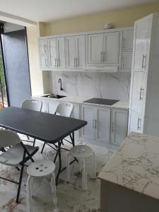 a kitchen with white cabinets and a table and chairs at JMC4 Cozy Room1 Near Alona Beach in Panglao